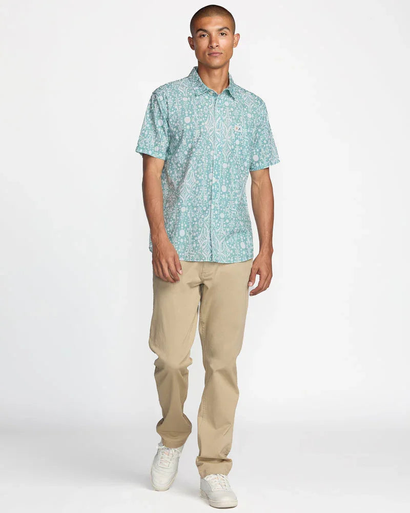 Man wearing teal patterned short sleeve shirt with khaki pants and white sneakers, coastal outdoor style