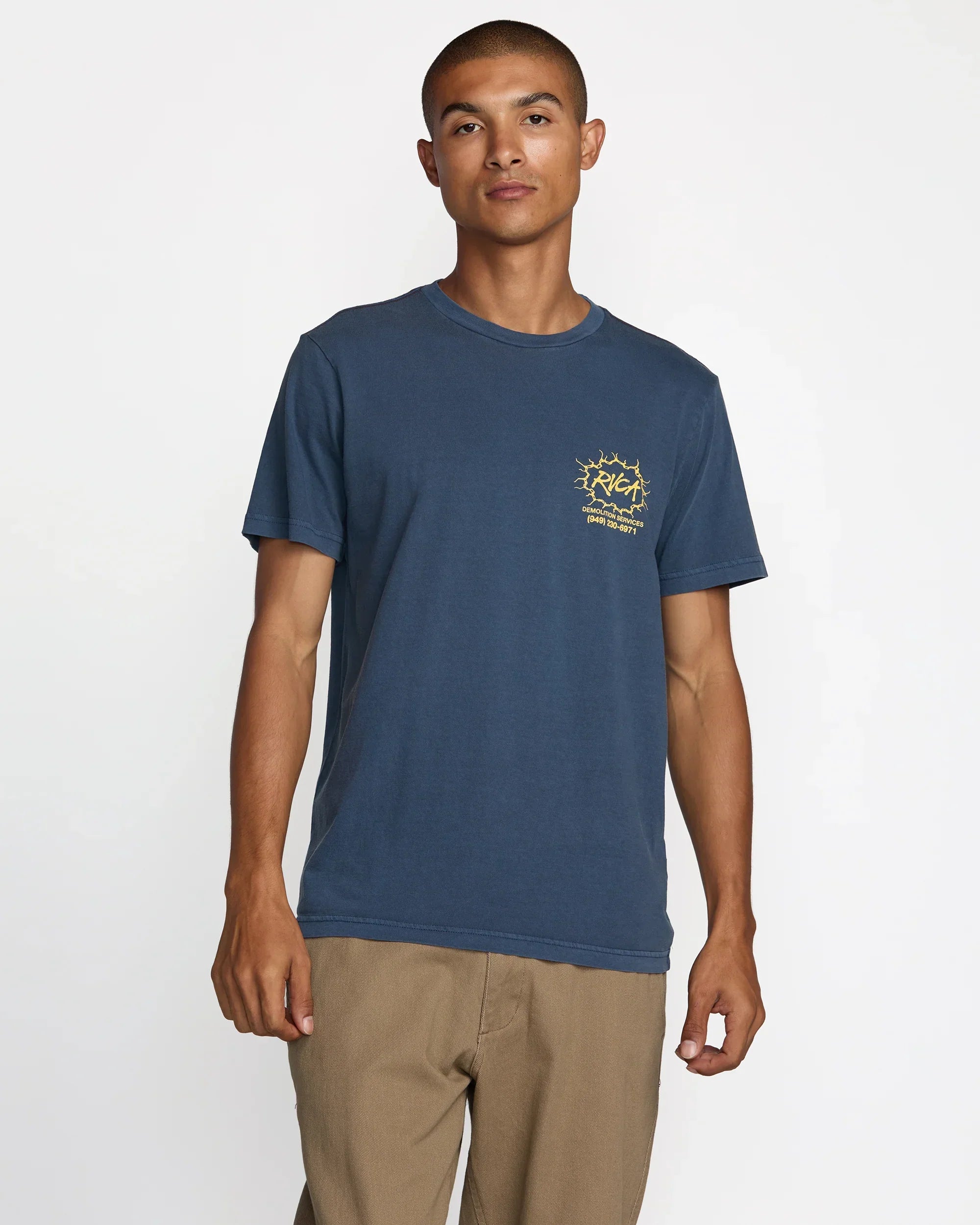 Man wearing navy blue RVCA t-shirt with yellow graphic, coastal style outdoor apparel
