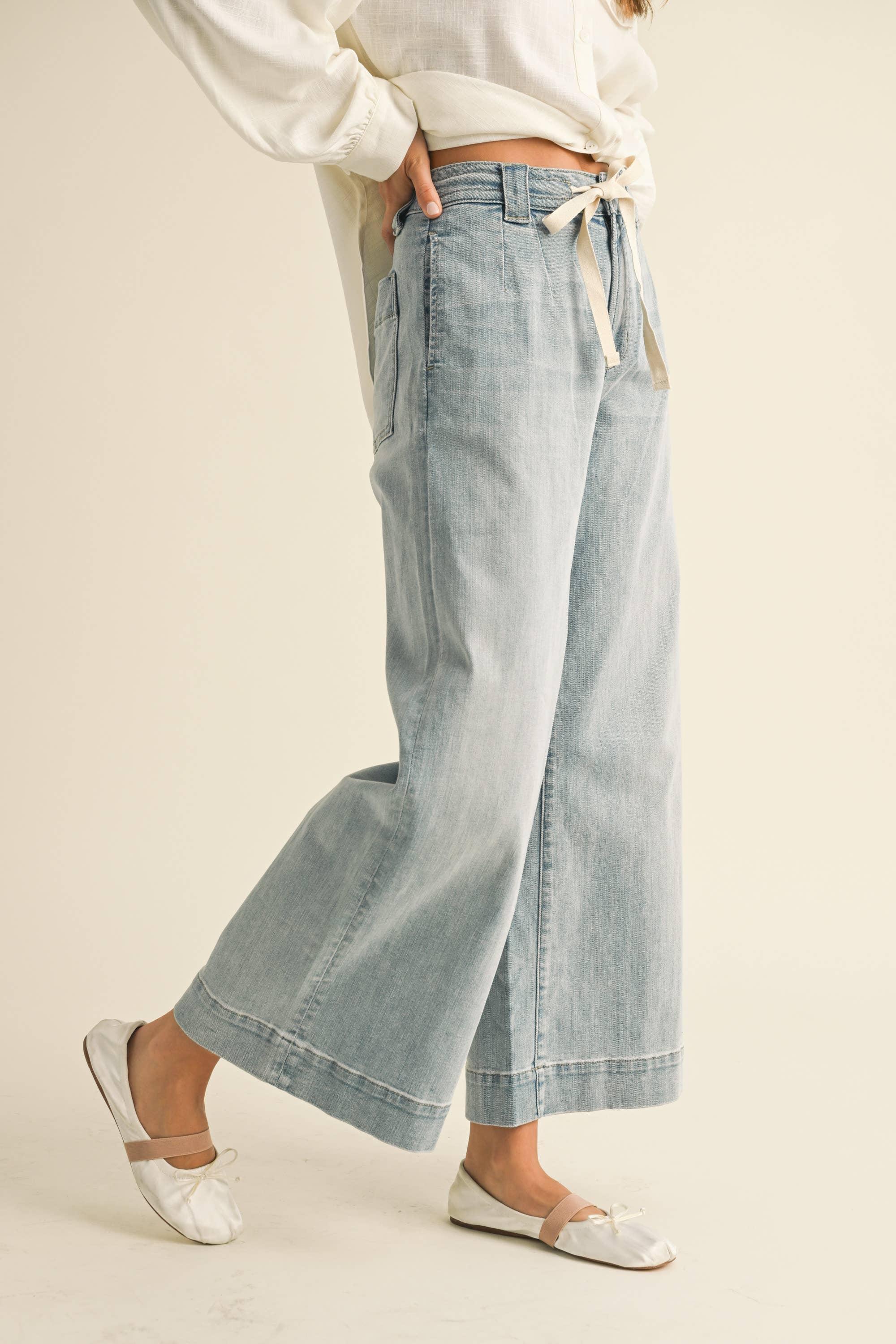 Light wash wide-leg denim jeans with tie waist, paired with white blouse and ballet flats