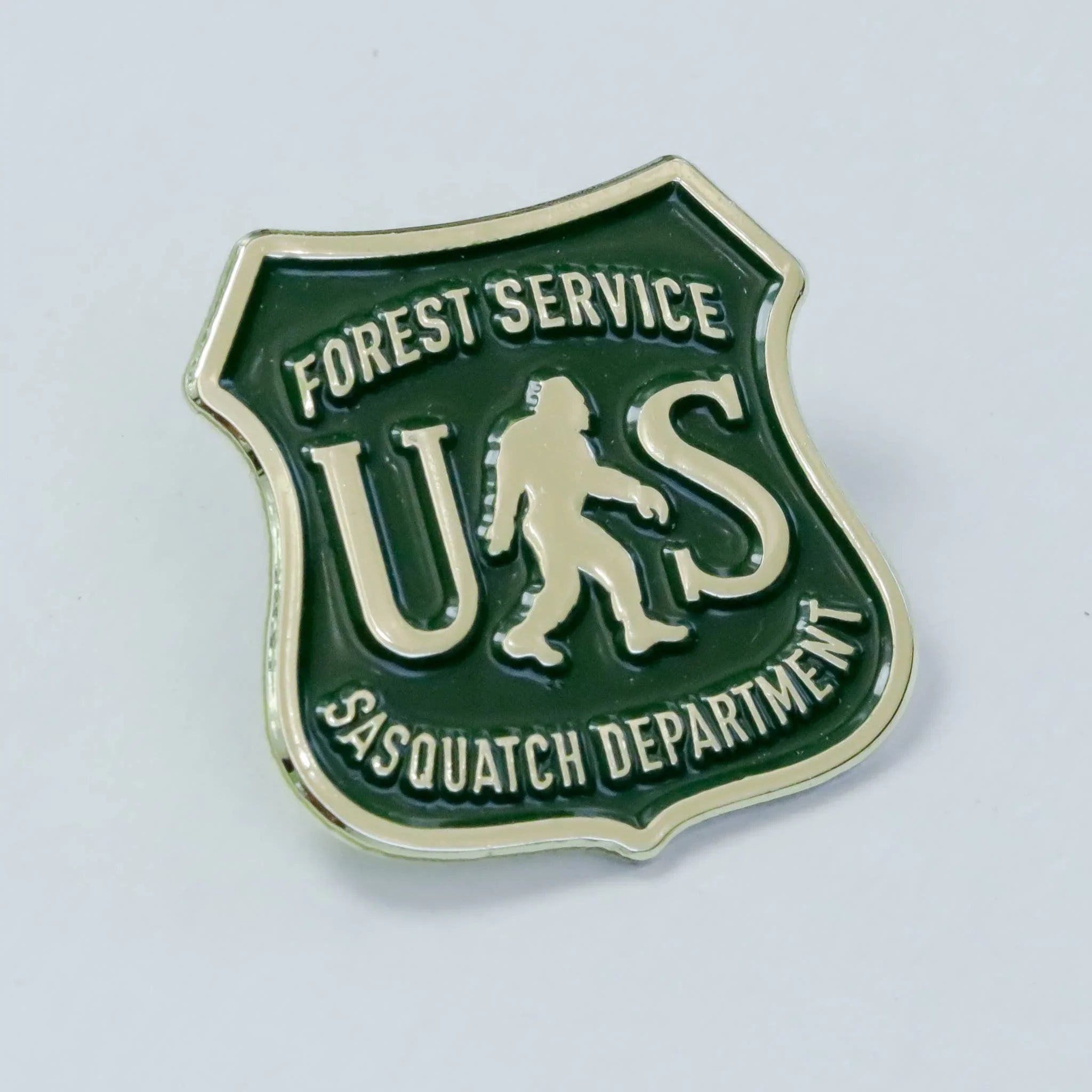 Forest Service US Sasquatch Department badge pin with green and gold design