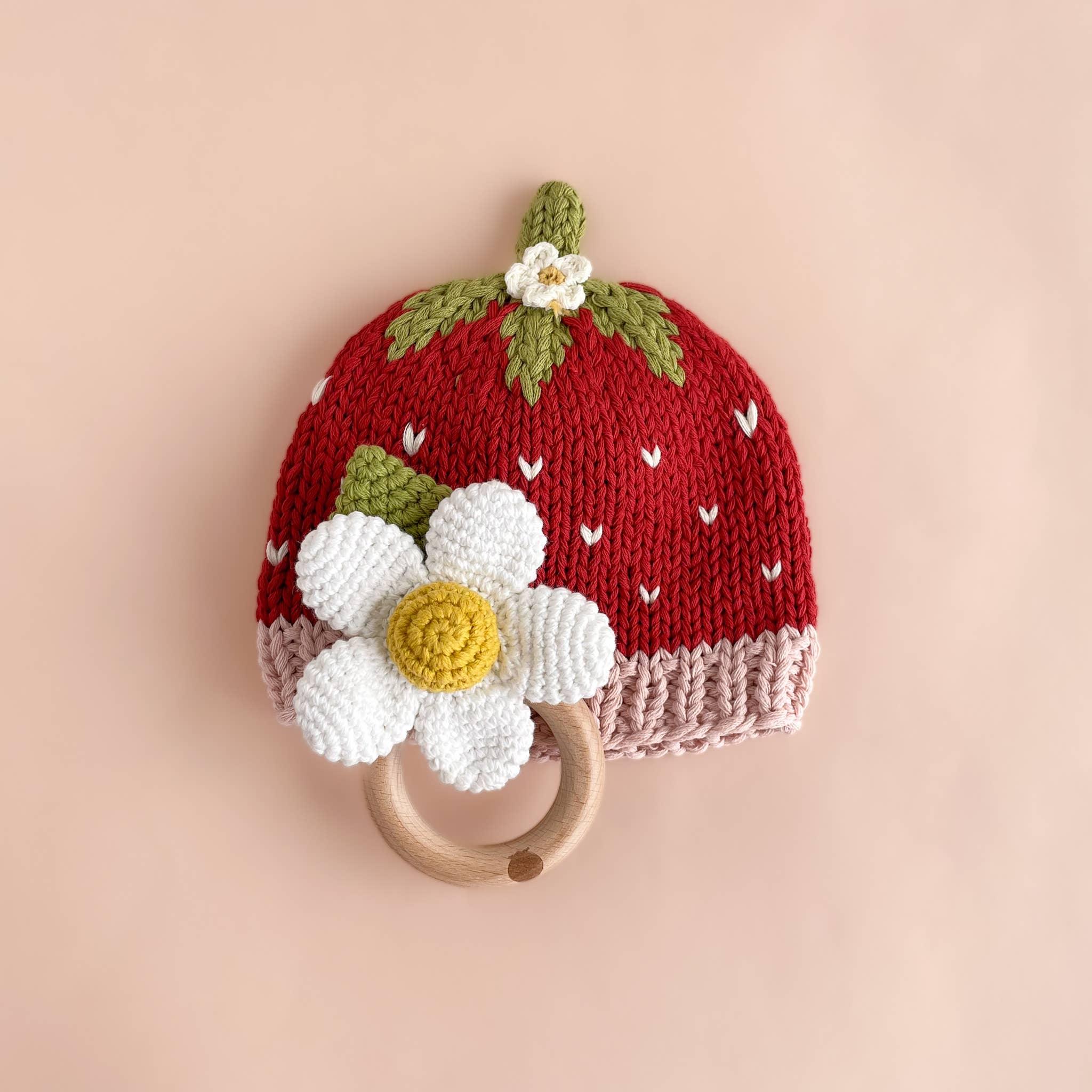 Strawberry-themed knit baby hat with daisy flower and wooden teether ring