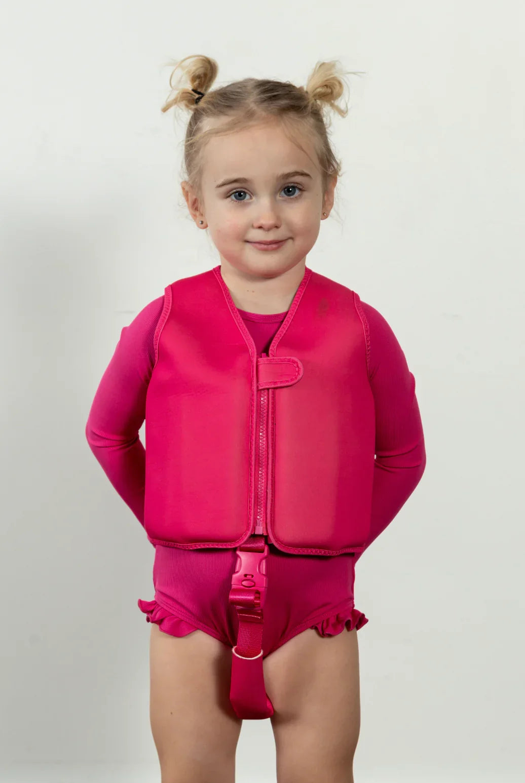 Child in pink swim vest and matching swimsuit, ready for water fun