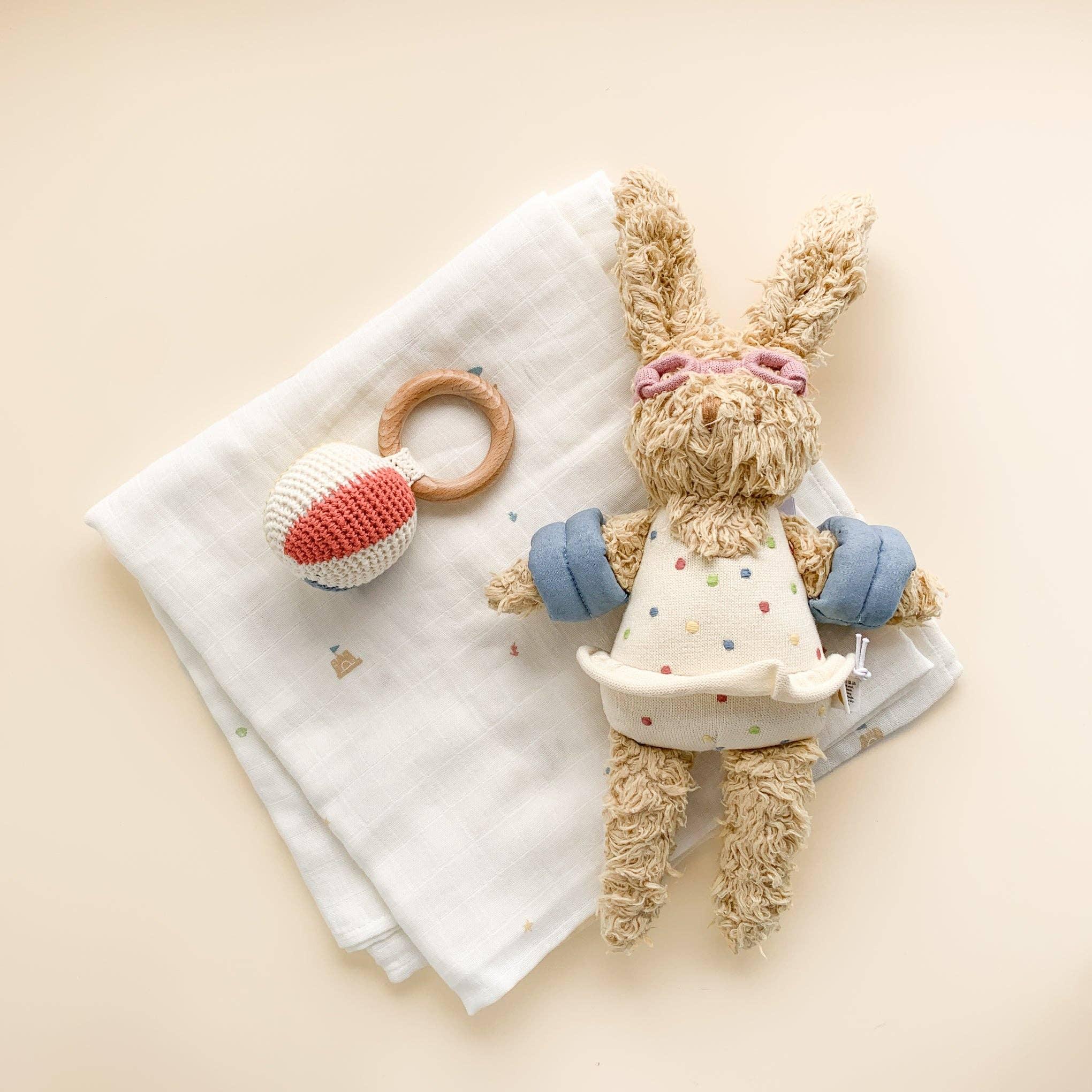 Soft bunny lovey with polka dot dress, wooden teether, and muslin blanket for baby comfort and play
