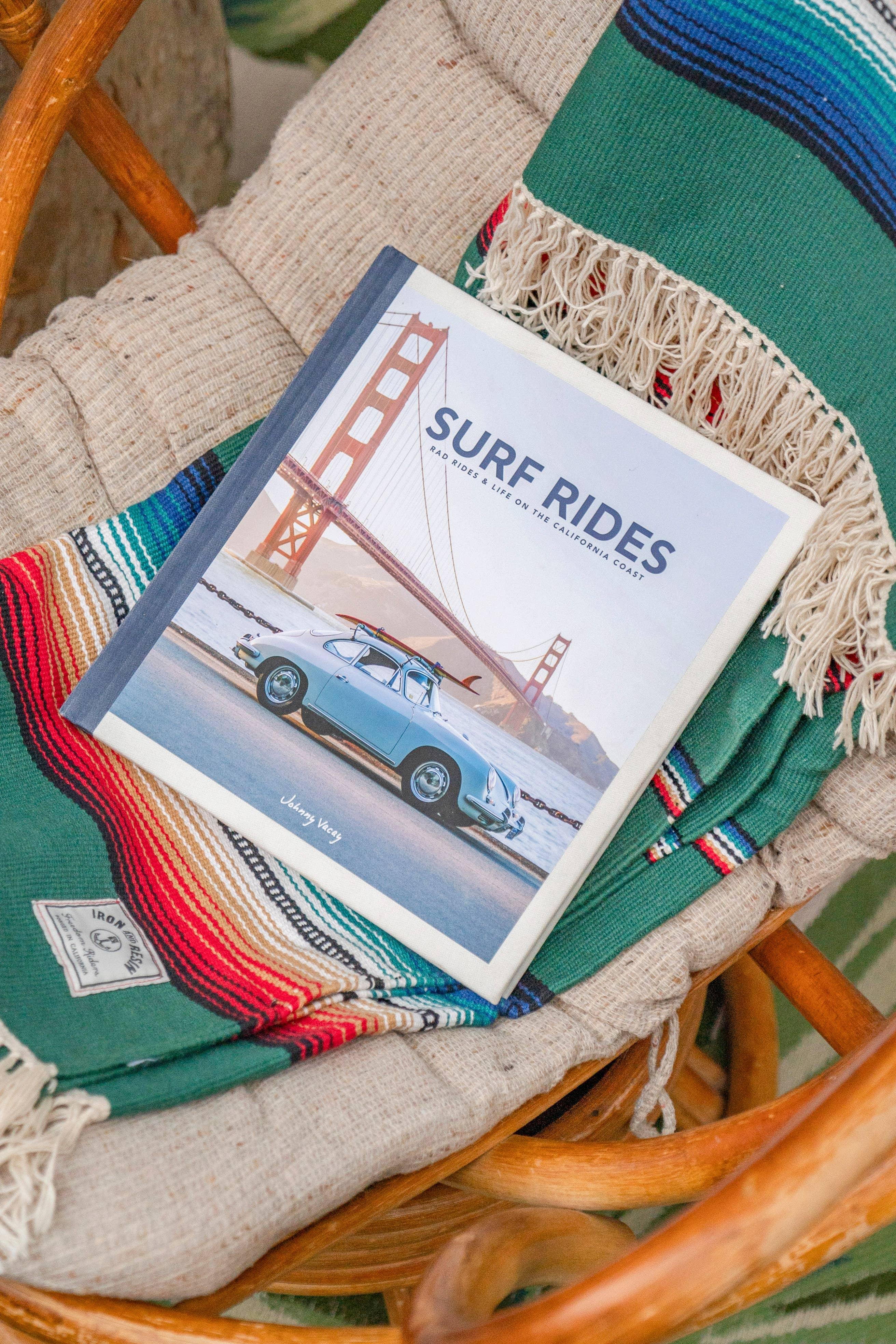 Surf Rides book on striped blanket in wicker chair, coastal lifestyle gear