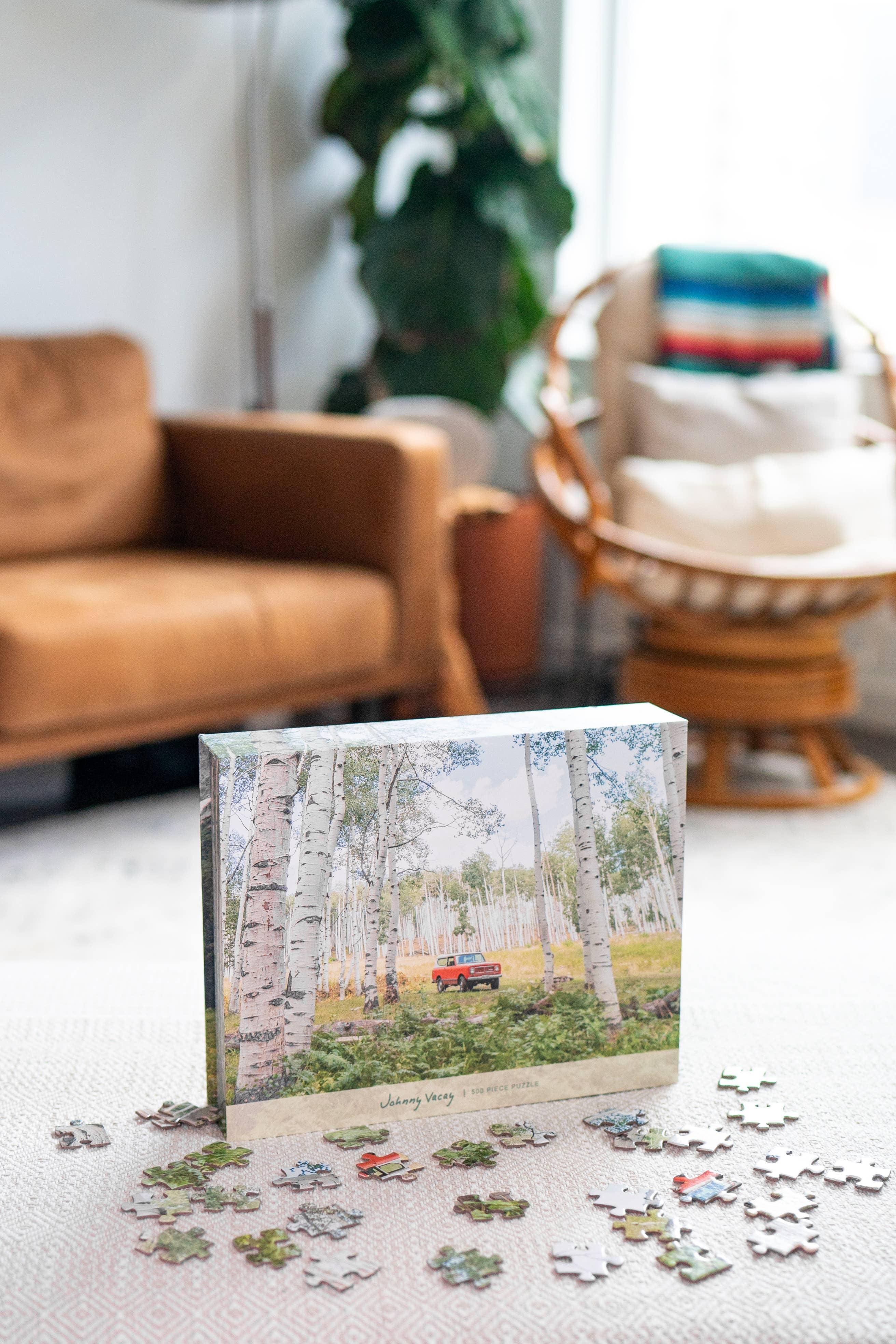 Johnny Vacay 500-piece puzzle featuring red truck in birch forest, cozy living room setting