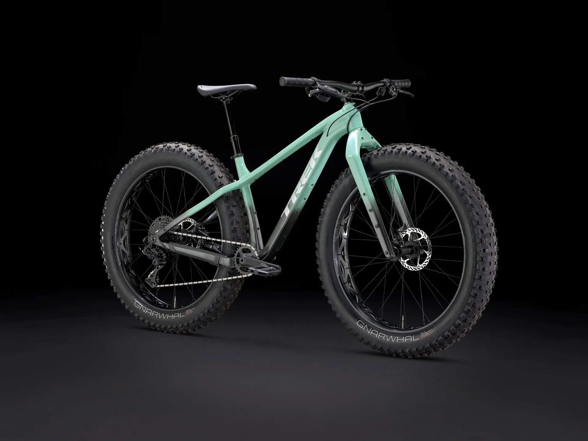 Mint green fat-tire mountain bike with wide GNARWHAL tires, sleek frame, and disc brakes on black background