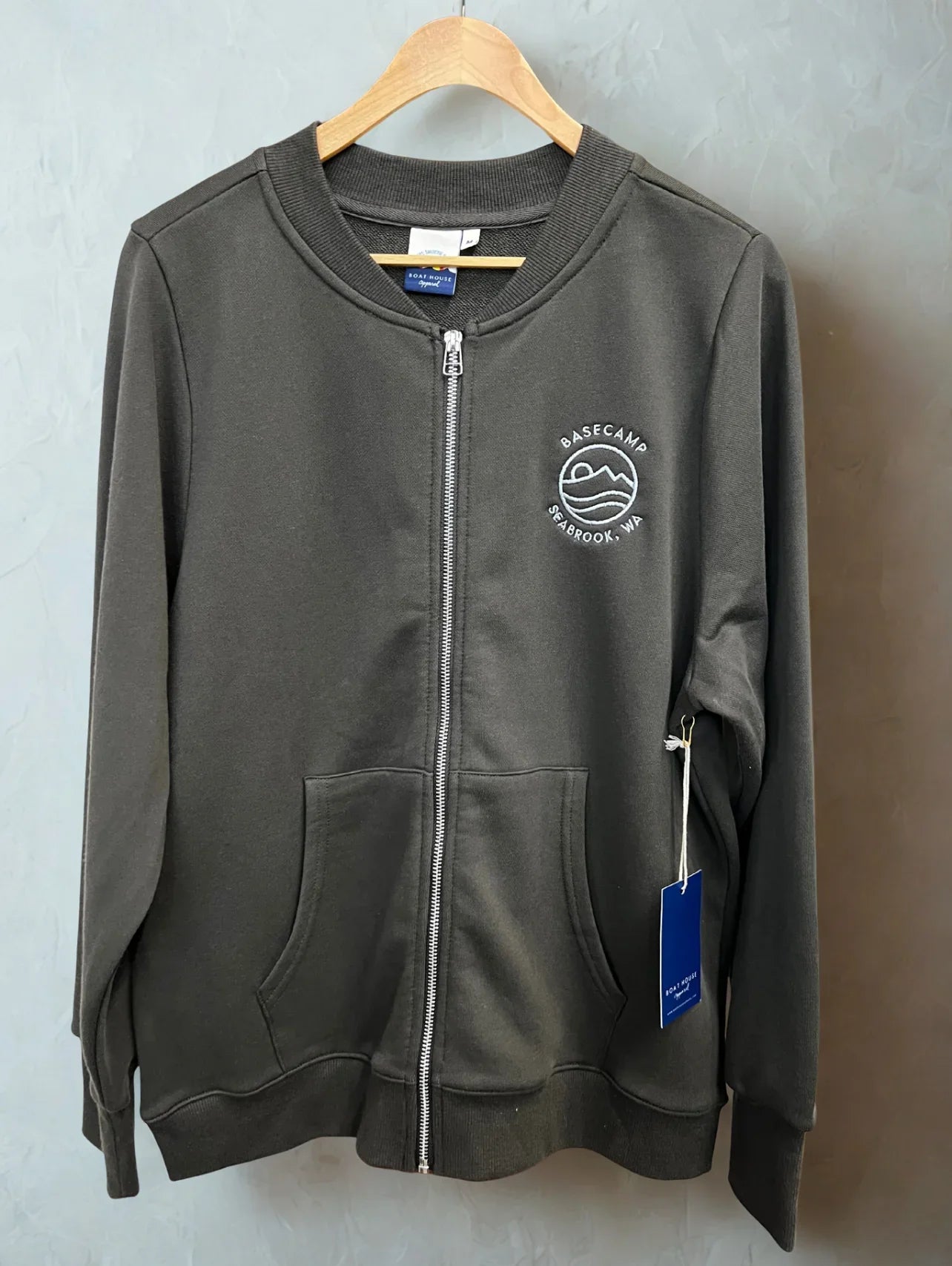 Dark gray zip-up hoodie with Basecamp Seabrook, WA logo, perfect for PNW outdoor adventures and coastal style.