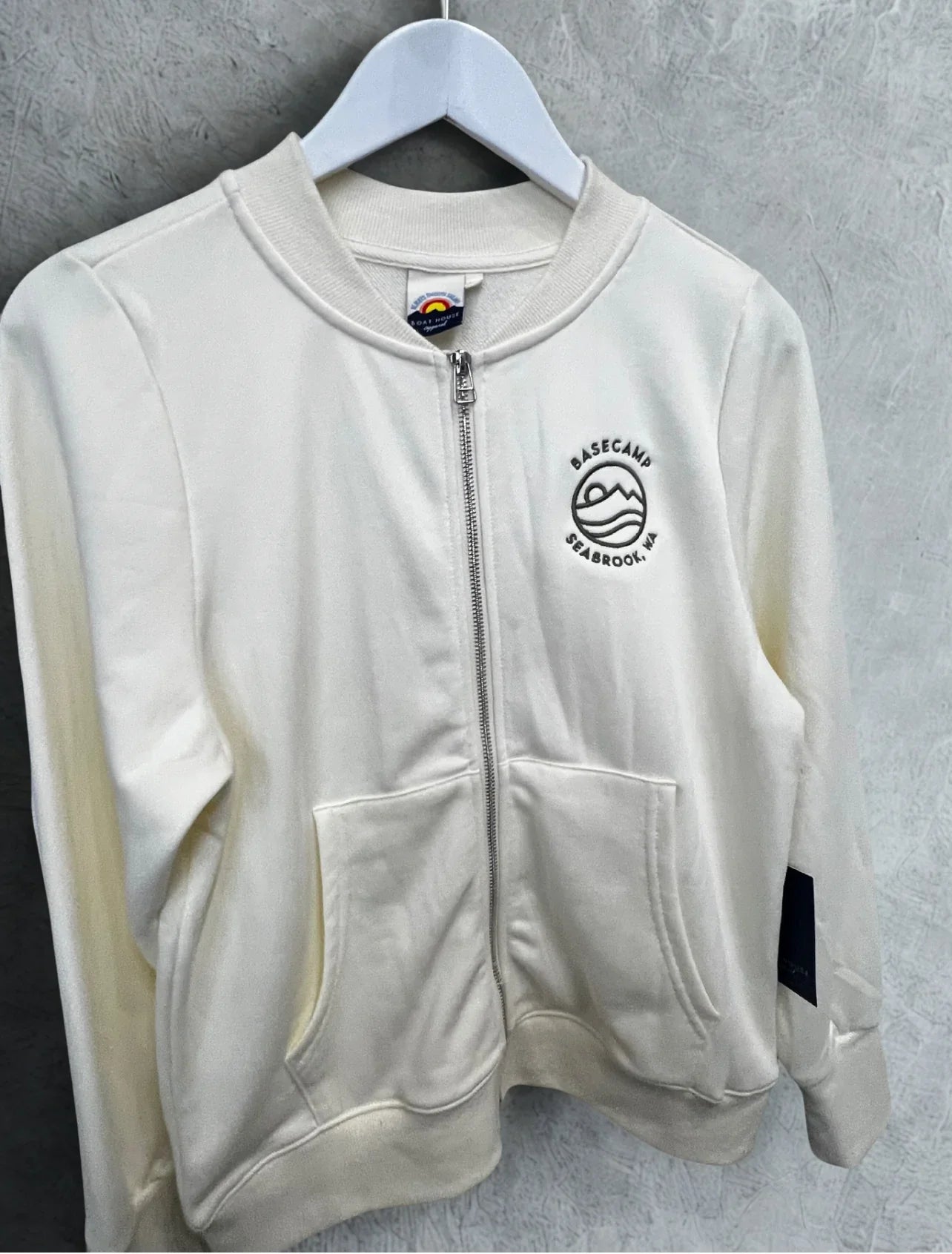 Cream zip-up hoodie with Basecamp Seabrook, WA logo, perfect for PNW outdoor adventures and coastal style.