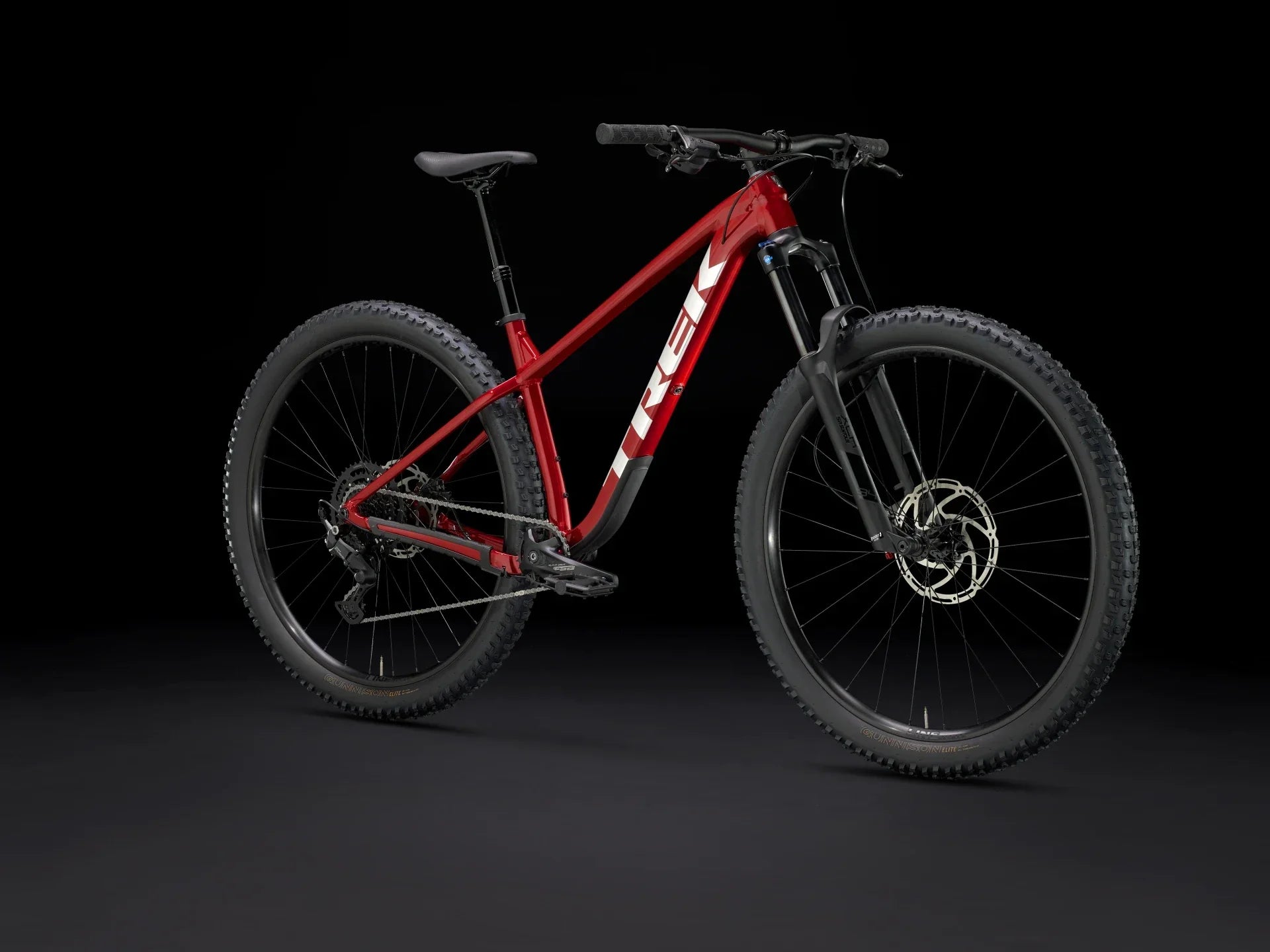 Red Trek mountain bike with rugged tires and front suspension, ideal for off-road adventures