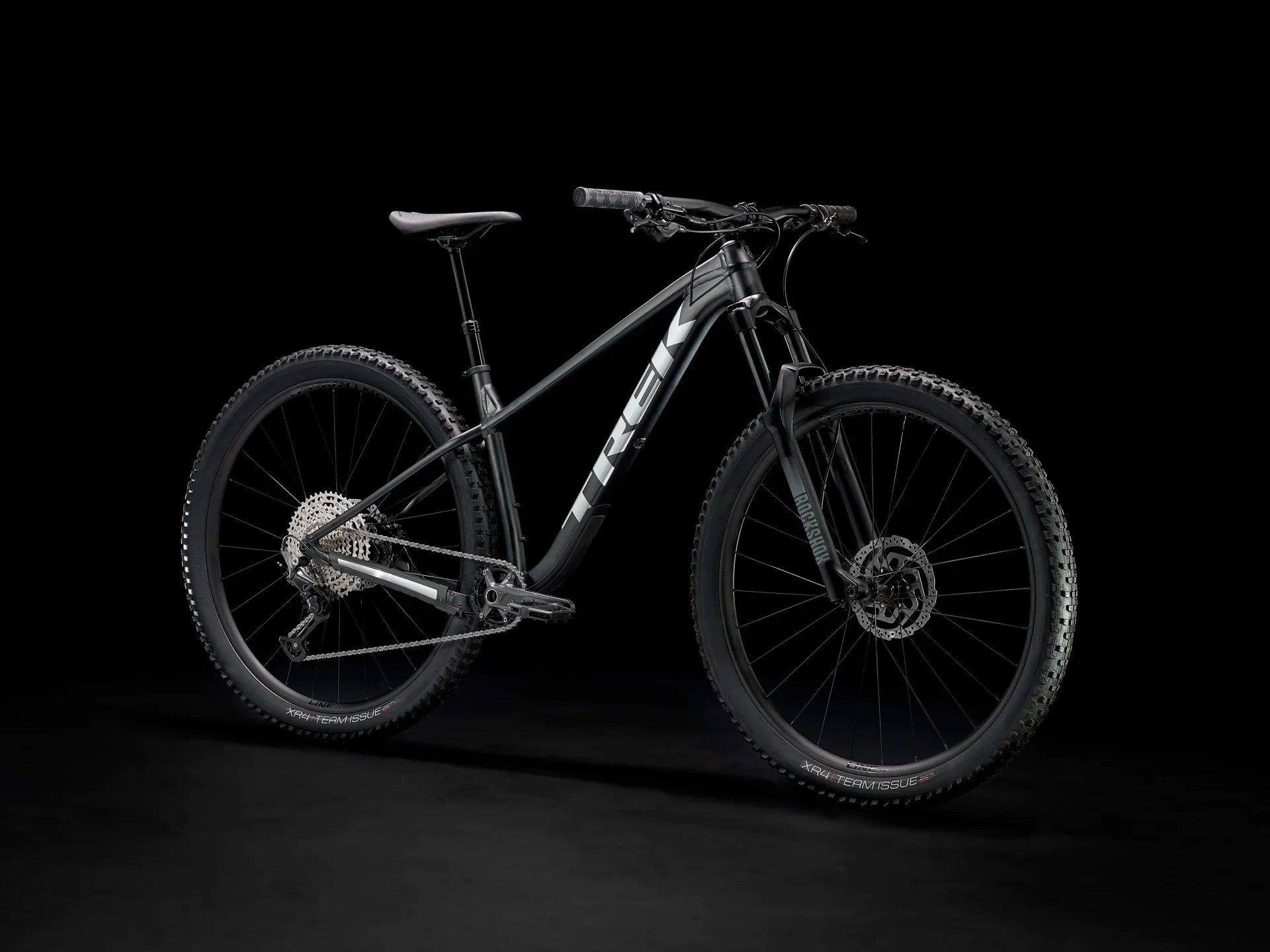 Black Trek mountain bike with RockShox suspension and XR4 Team Issue tires on dark background