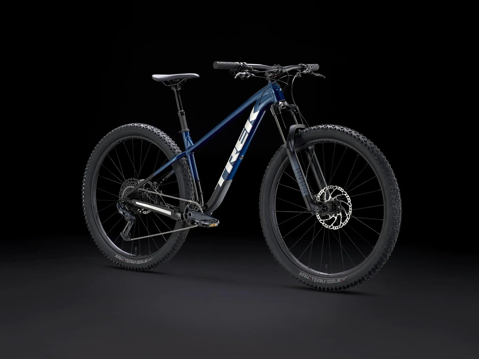 Blue Trek mountain bike with RockShox suspension and XR4 Team Issue tires on black background
