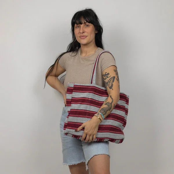 Woman holding striped woven tote bag, perfect for beach days and coastal adventures