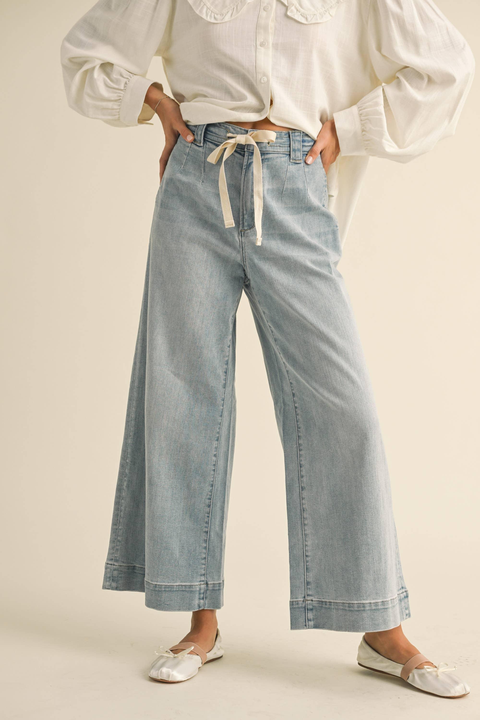 Light wash wide-leg jeans with tie waist, paired with ruffled blouse and ballet flats