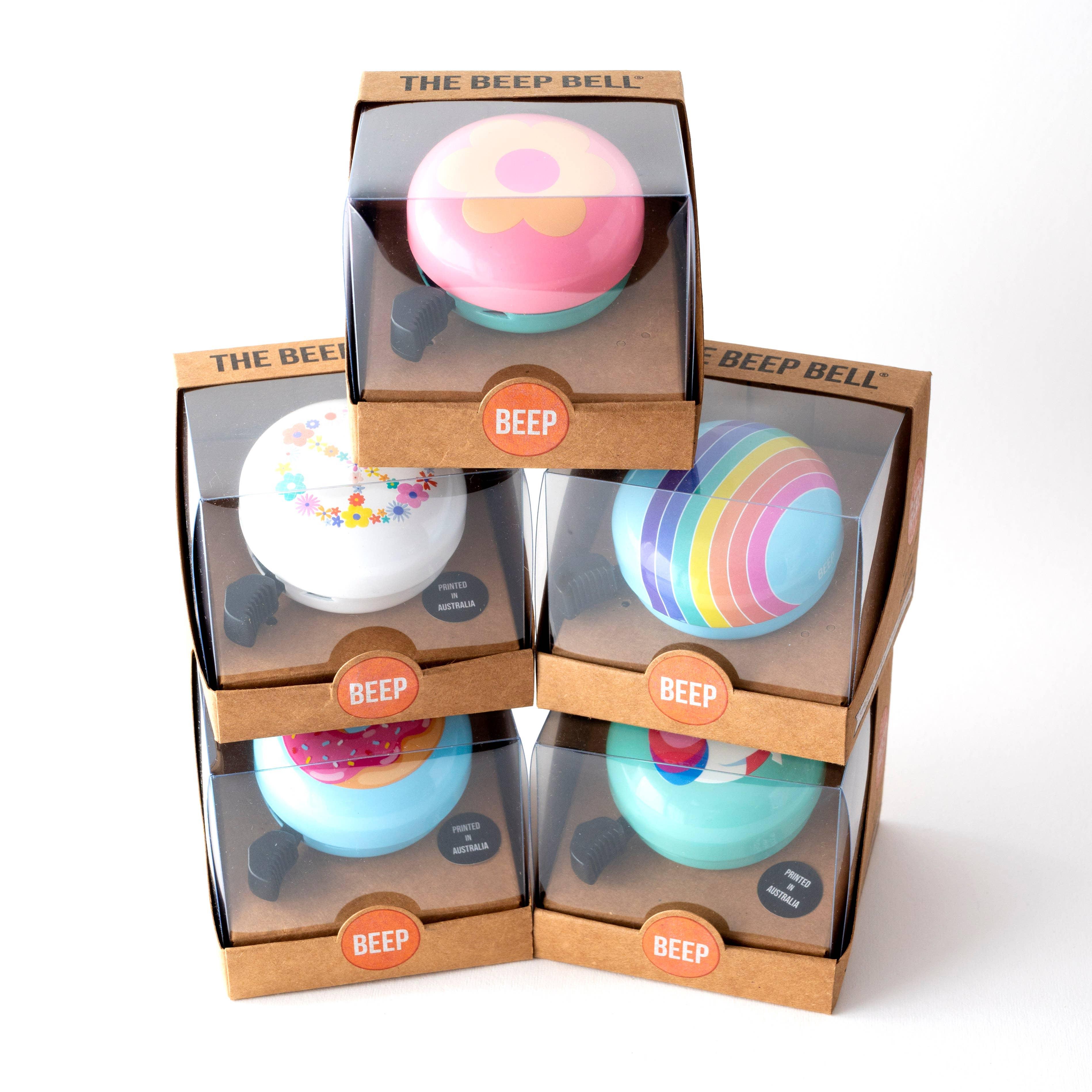 Colorful Beep Bell bike bells in floral, rainbow, donut designs, packaged for outdoor adventures