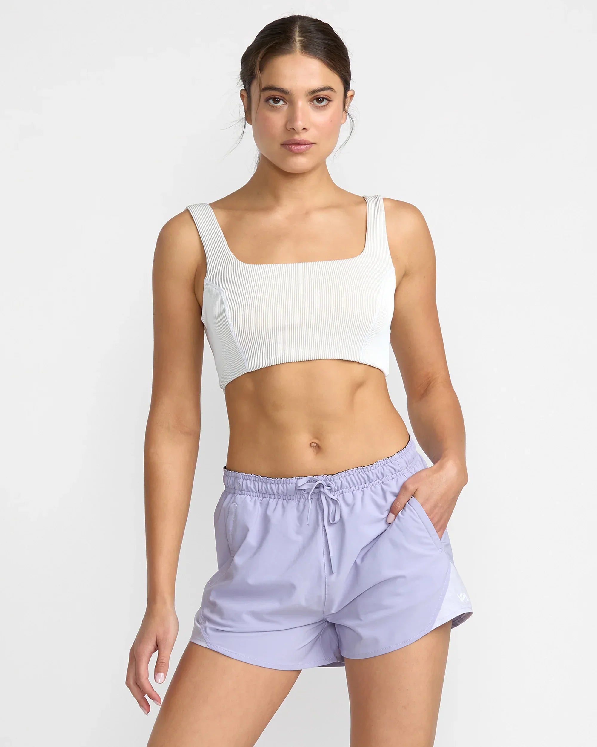 Woman in white ribbed crop top and lavender drawstring shorts, coastal active wear
