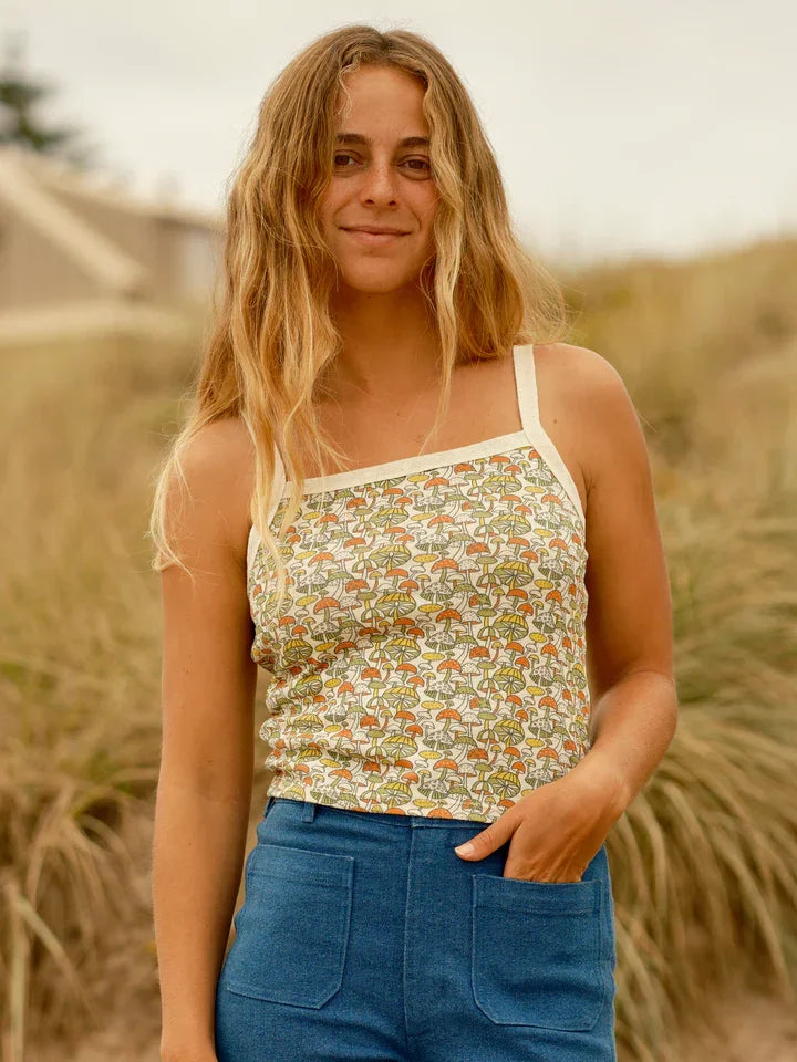 Woman in mushroom-print tank top and blue denim shorts, coastal outdoor style