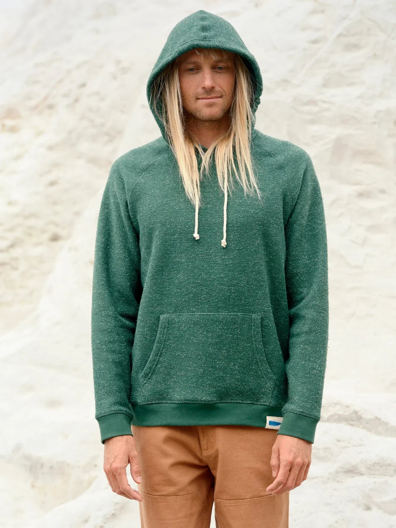 Man in green hooded sweatshirt with drawstring, standing outdoors
