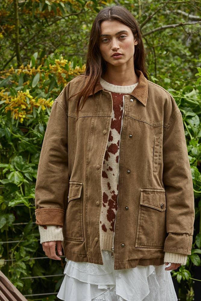 Brown corduroy jacket with button front, worn over cow print sweater and white skirt, outdoors