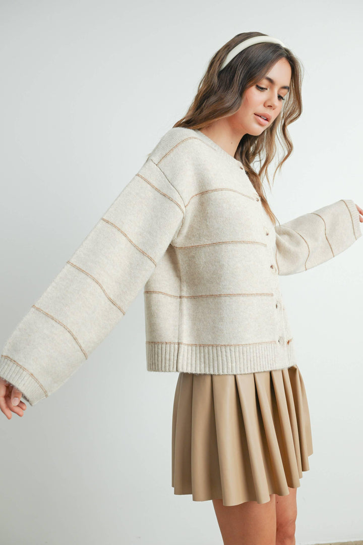 Cream button-front cardigan with contrast stitching, paired with pleated skirt and headband for coastal style