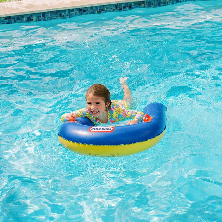 Child floating in pool on blue and yellow Little Tikes swim ring, enjoying summer fun.