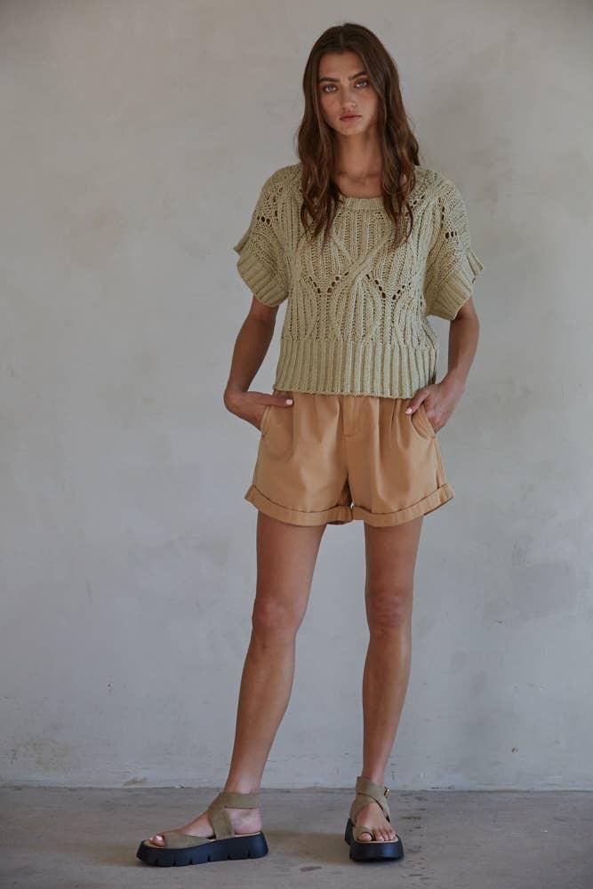 Woman in olive knit top, tan shorts, and platform sandals, casual summer outfit