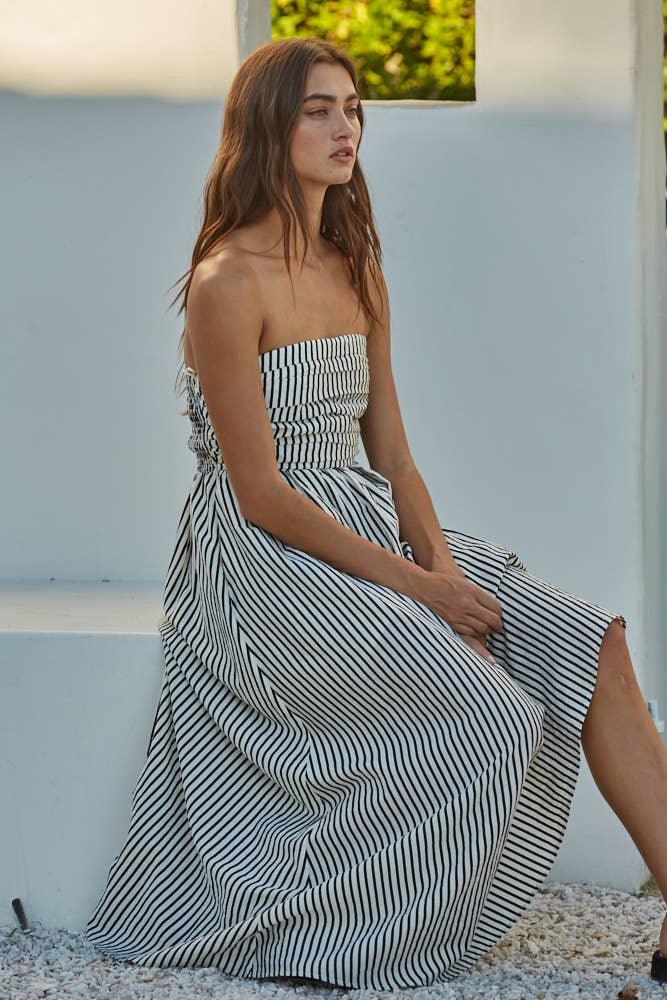 Woman in black and white striped strapless maxi dress, coastal outdoor setting