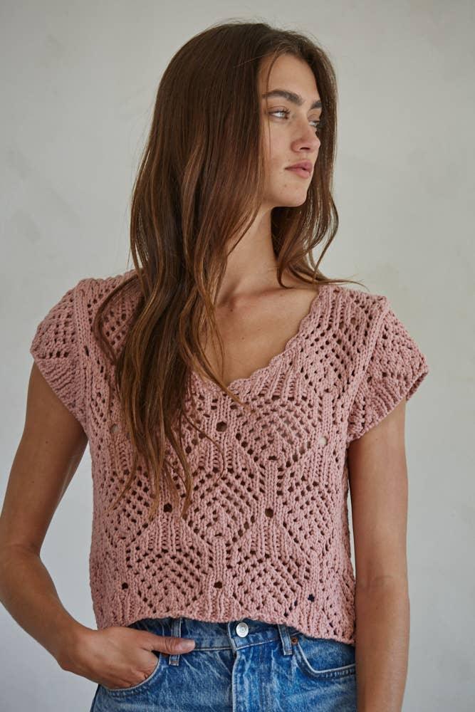 Pink crochet top with V-neck and short sleeves, paired with blue jeans