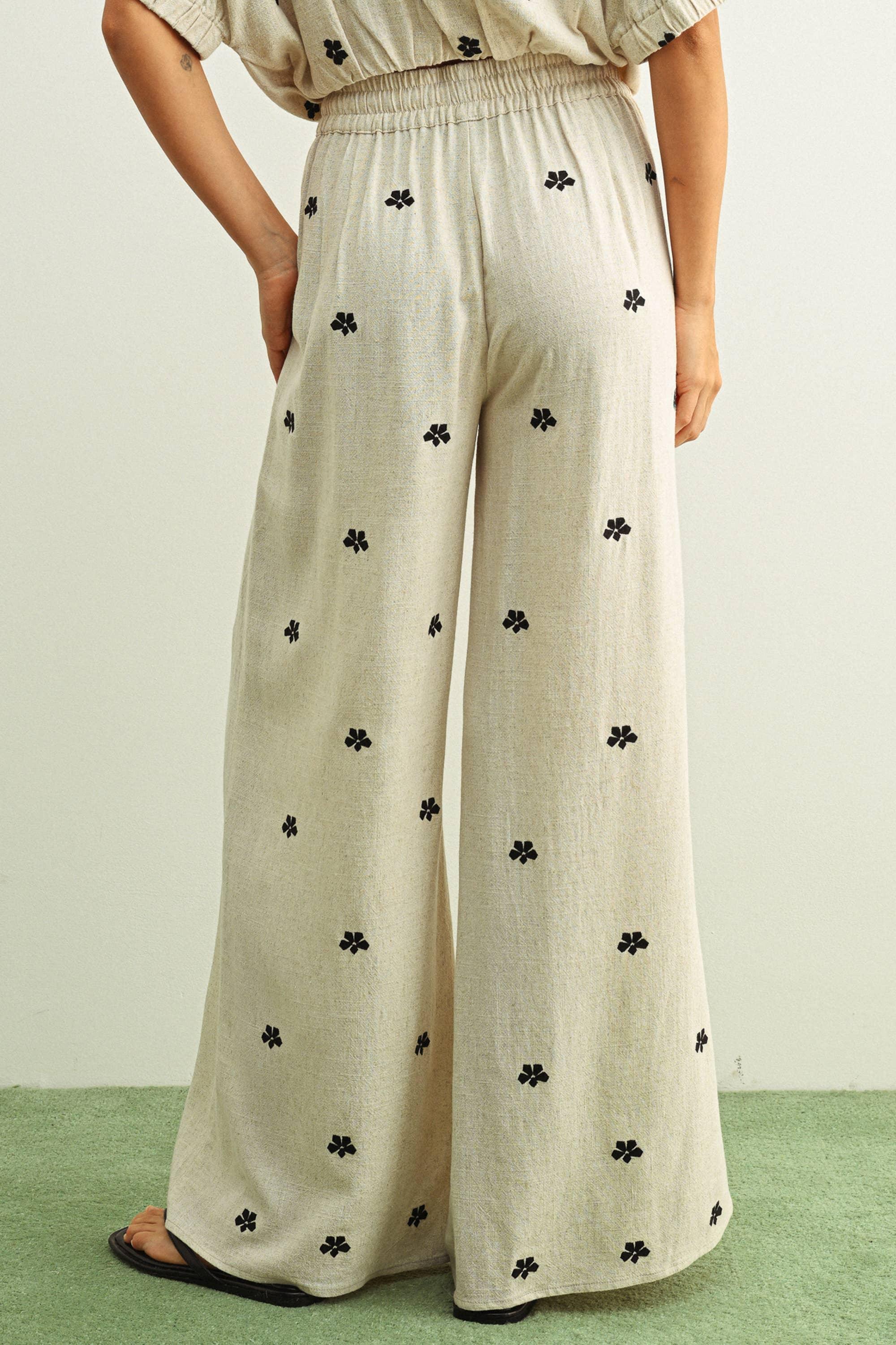 Beige wide-leg pants with black floral print, elastic waist, paired with matching top and sandals