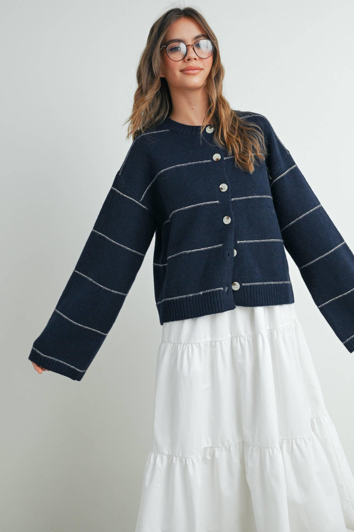 Navy striped button-front cardigan with white contrast stitching, paired with tiered white skirt for coastal style