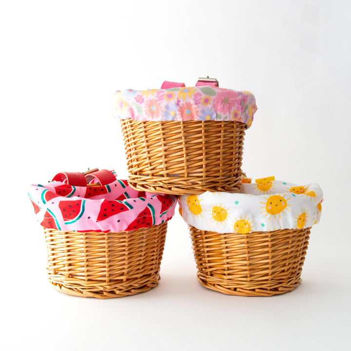 Three wicker bike baskets with colorful liners: watermelon, sun, and floral patterns for outdoor adventures.