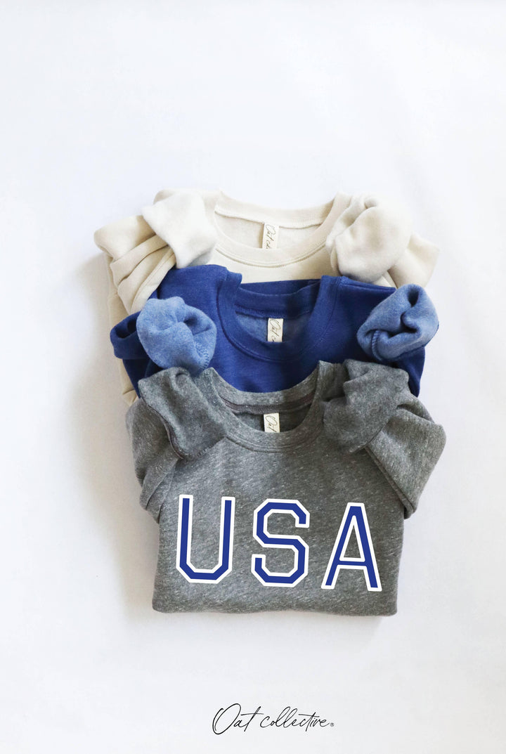 Stacked USA graphic tees in gray, blue, and cream for coastal PNW style