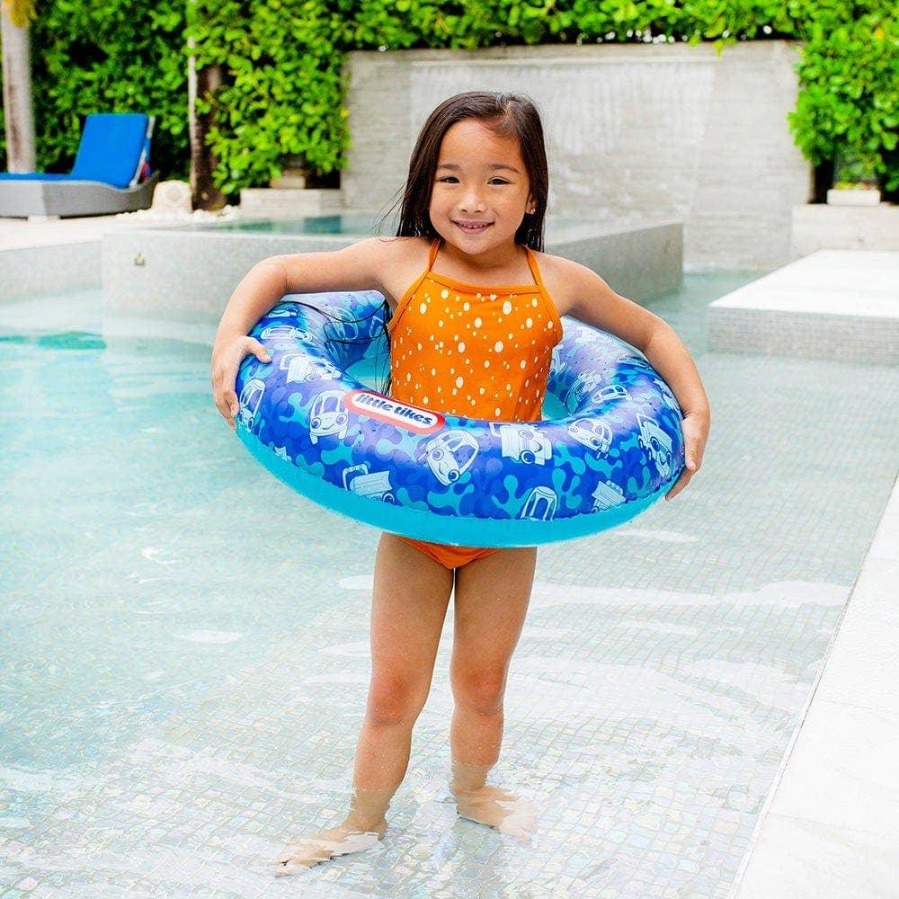 Child holding blue swim ring with car patterns by poolside