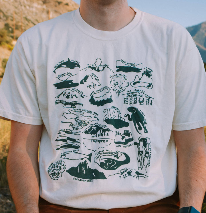 White t-shirt with PNW map graphic featuring mountains, rivers, and landmarks for outdoor adventures.