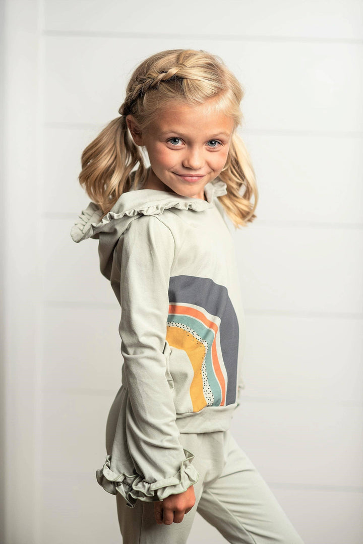 Girl wearing an Oopsie Daisy gray sage rainbow hooded sweatsuit lounge set