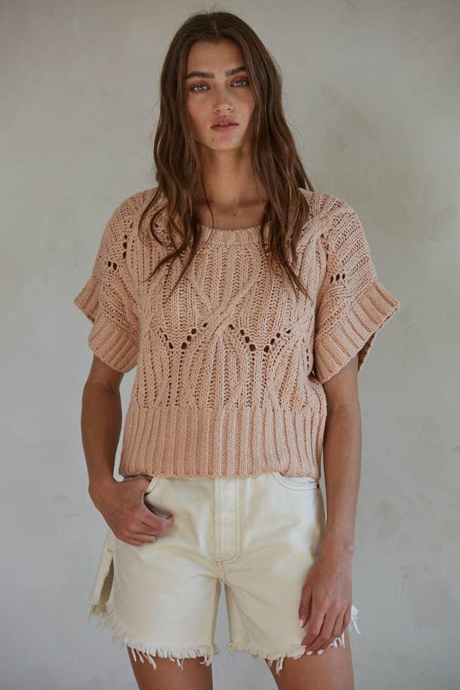 Woman wearing blush knit crop top with lace detailing and cream denim shorts