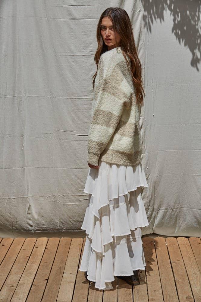 Woman in cozy striped sweater and white ruffle skirt, coastal outdoor style
