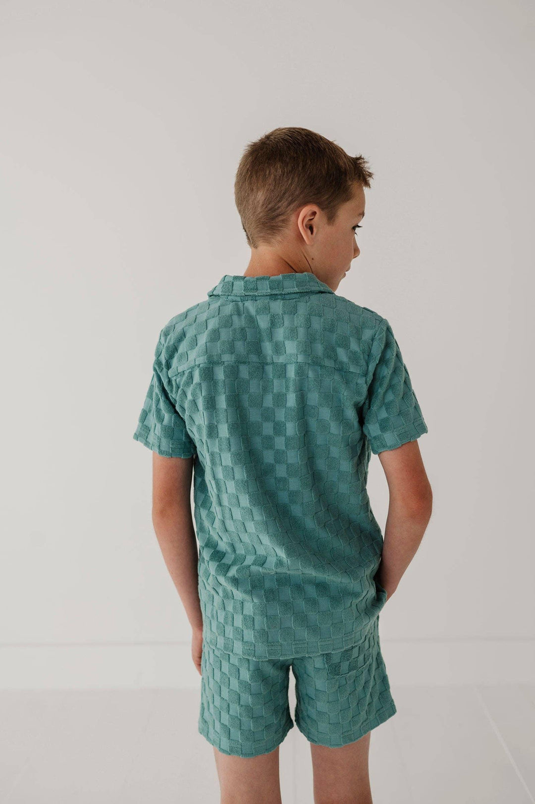Boy in teal woven texture short sleeve pajama set, back view