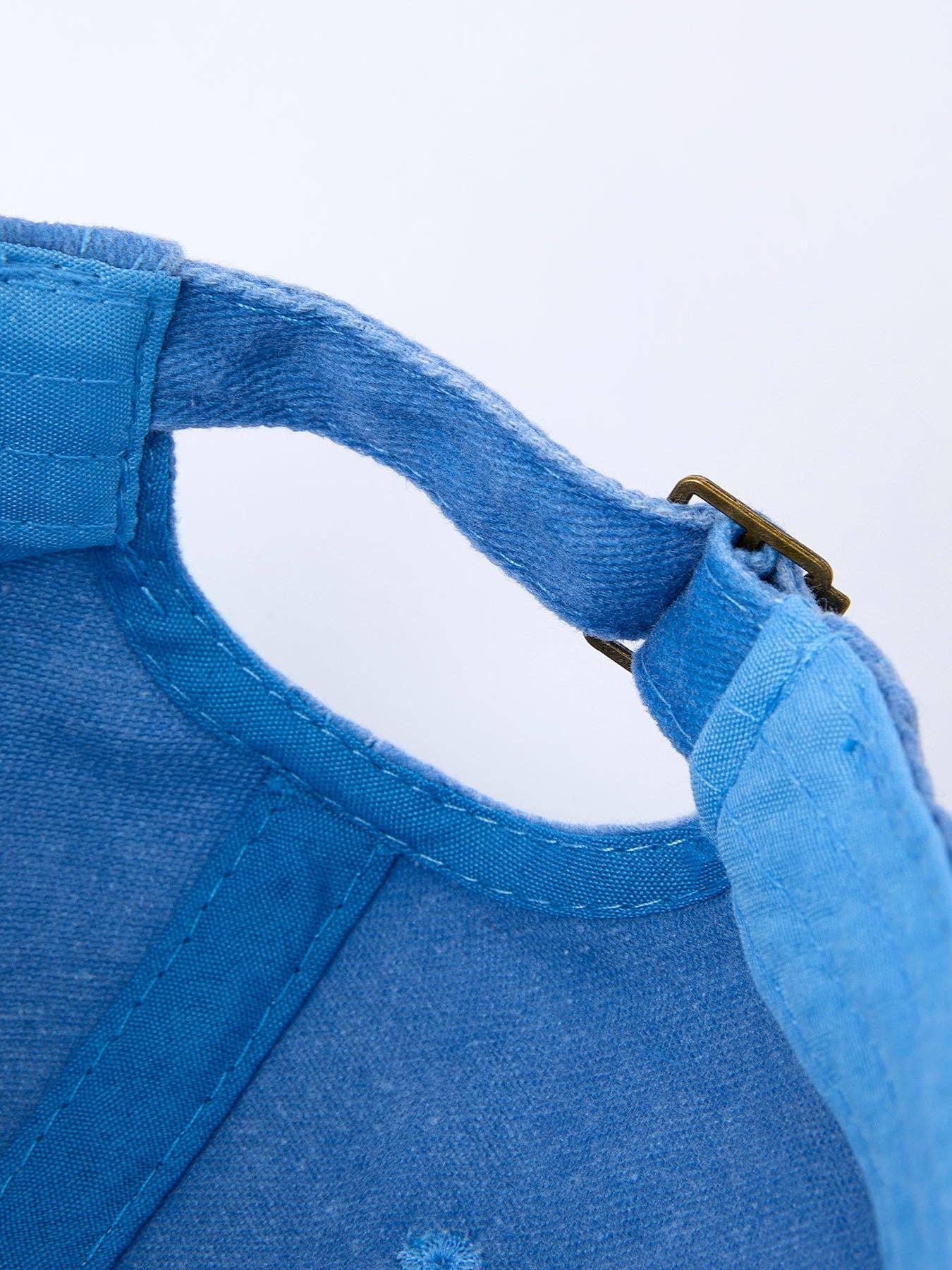 Blue washed canvas hat with brass buckle strap, perfect for coastal adventures and outdoor style.