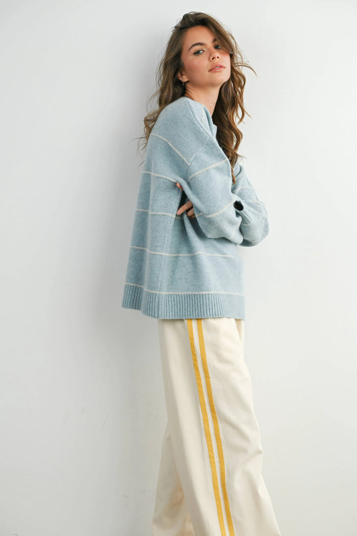 Woman in light blue striped sweater and cream pants with yellow side stripes, coastal style outfit