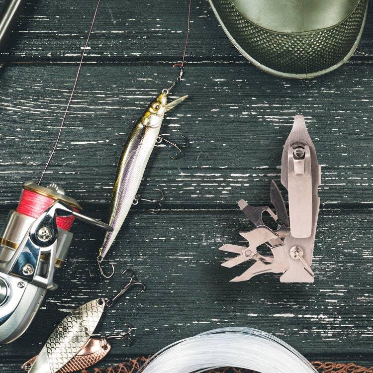 Fishing lure, reel, line, and multi-tool on rustic wood — coastal outdoor gear essentials