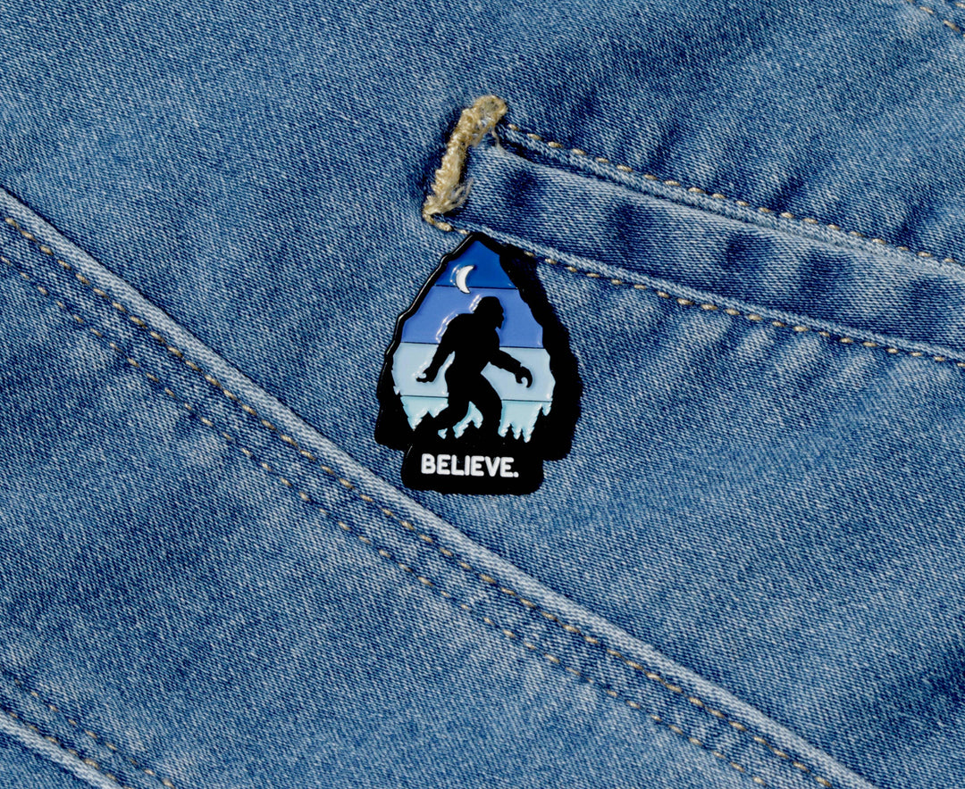 Believe Bigfoot enamel pin on denim jeans, outdoor adventure accessory