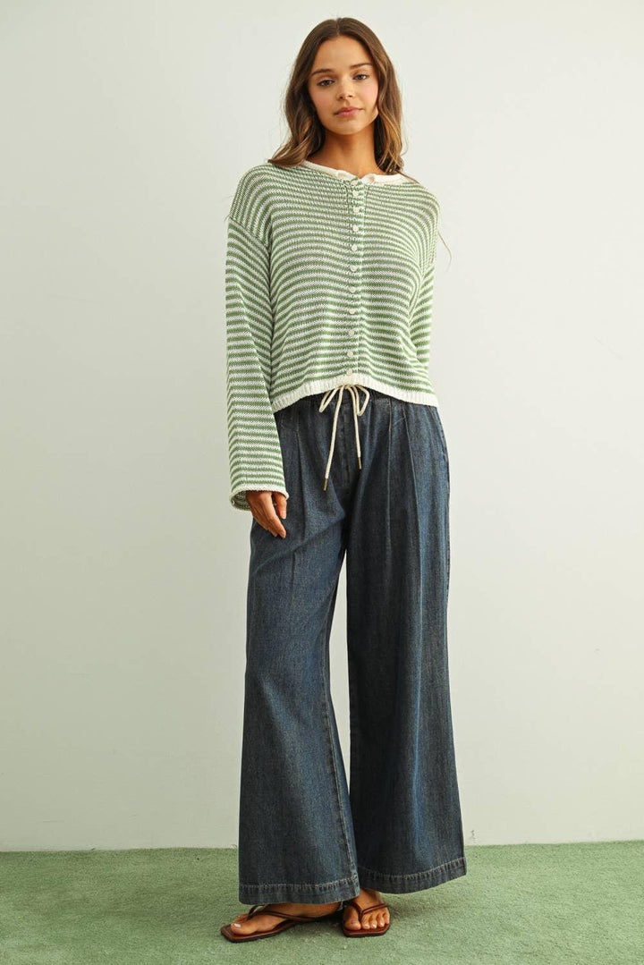Woman wearing green striped knit cardigan with wide-leg denim pants and sandals