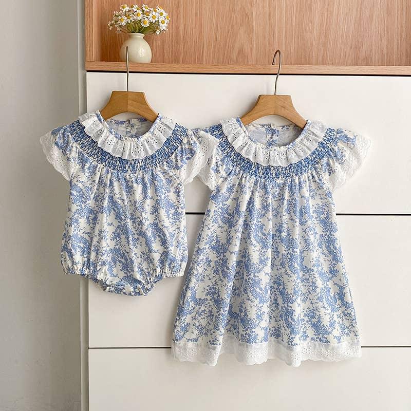 Blue floral baby romper and matching dress with lace trim, hanging on wooden hangers