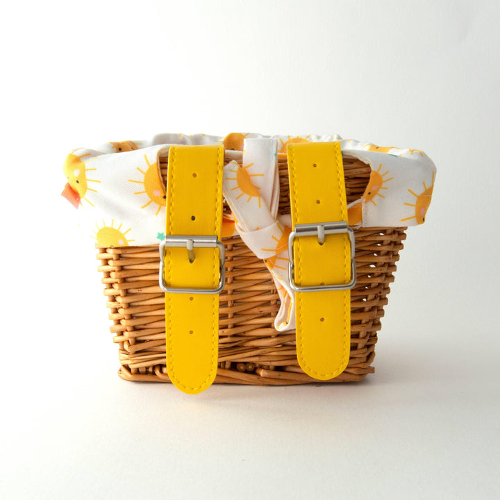 Woven bike basket with yellow straps and sun-patterned liner, perfect for beach days and outdoor adventures.