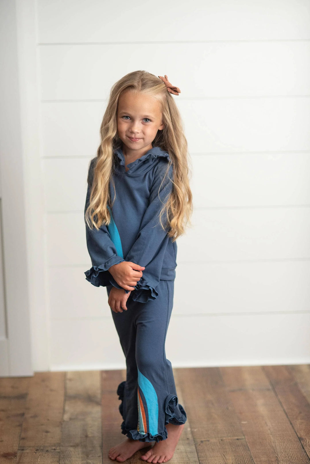 Girl in blue ruffle pajama set with teal stripe, cozy coastal kids loungewear