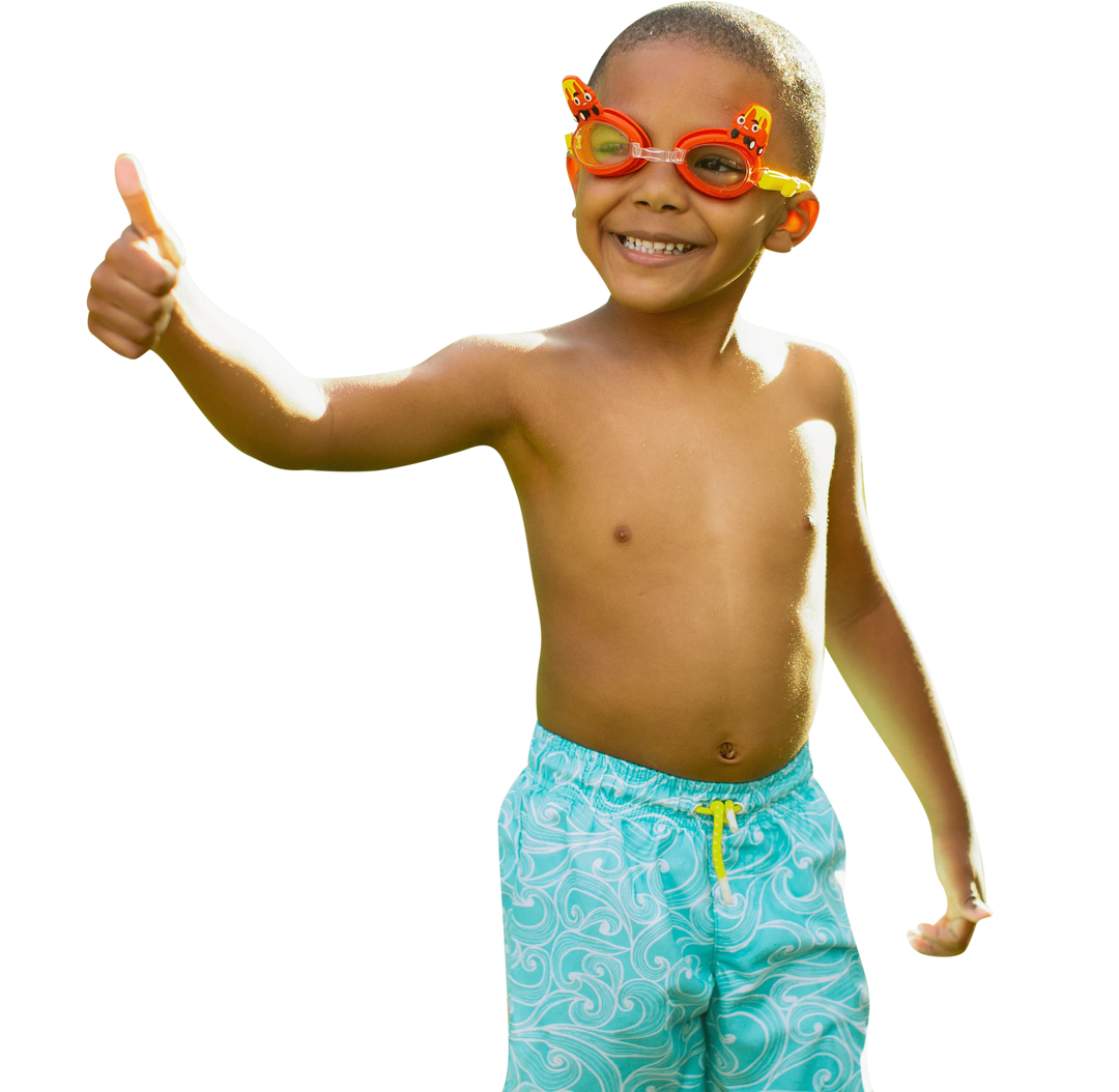 A smiling young boy wearing PoolCandy Little Tikes Cozy Coupe 3D swim goggles and blue swim trunks.