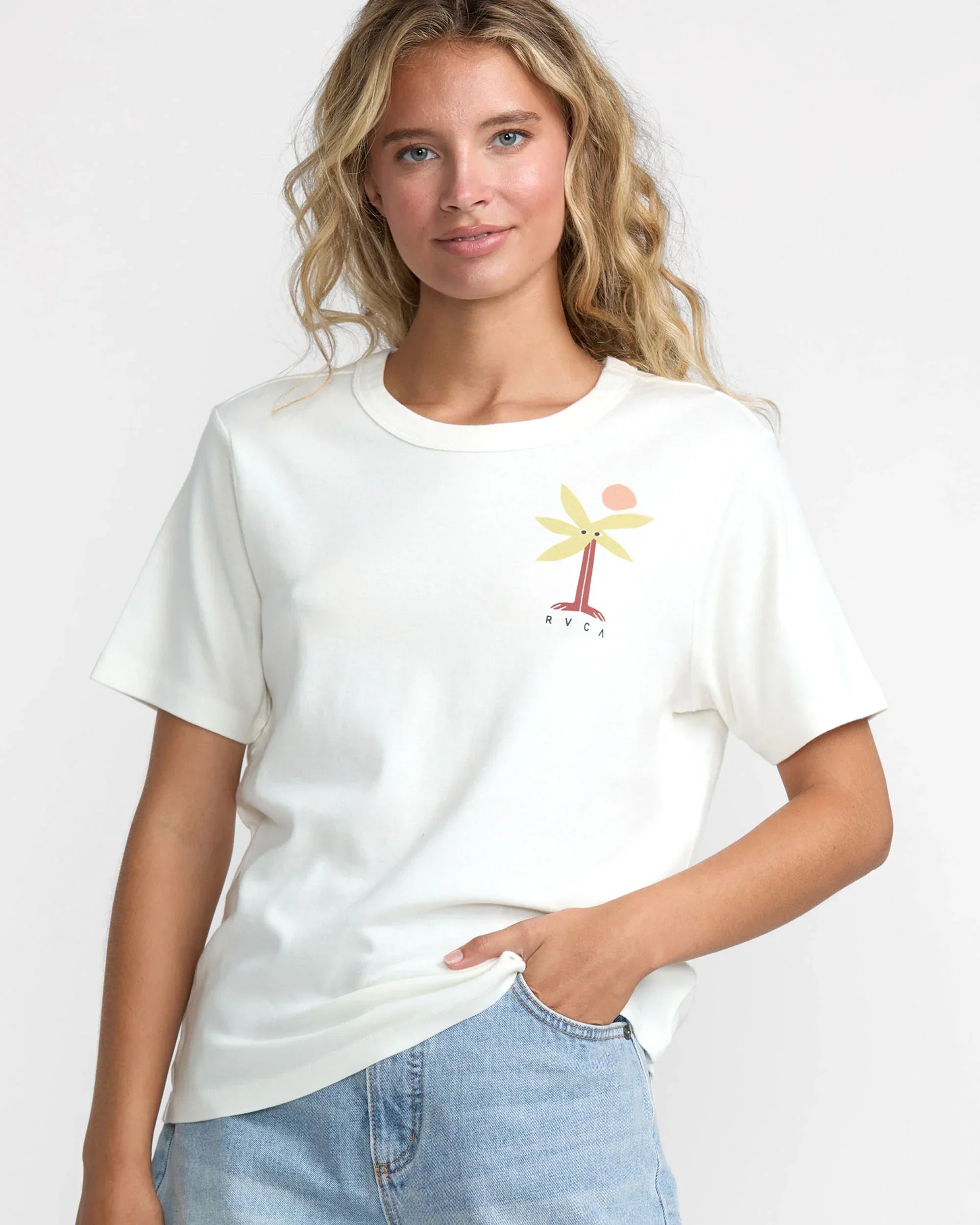 Woman wearing white RVCA palm tree graphic tee, coastal style outfit with denim shorts