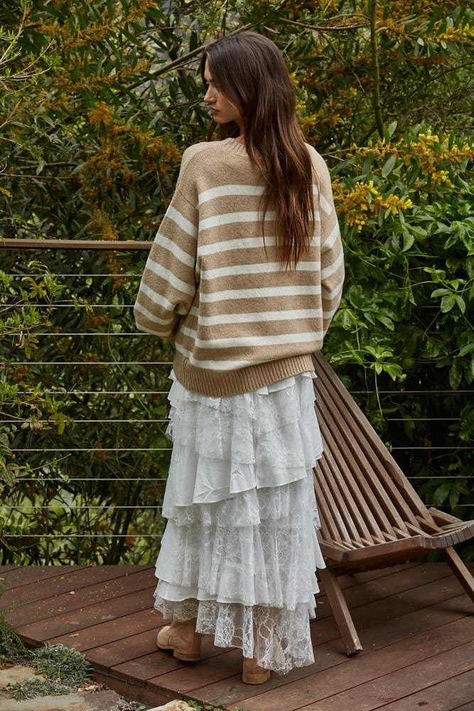 Woman in striped sweater and white lace skirt on wooden deck, coastal outdoor style