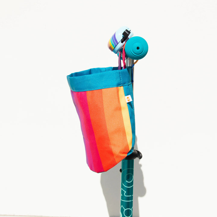 Rainbow-striped bike basket attached to scooter handlebars for outdoor adventures