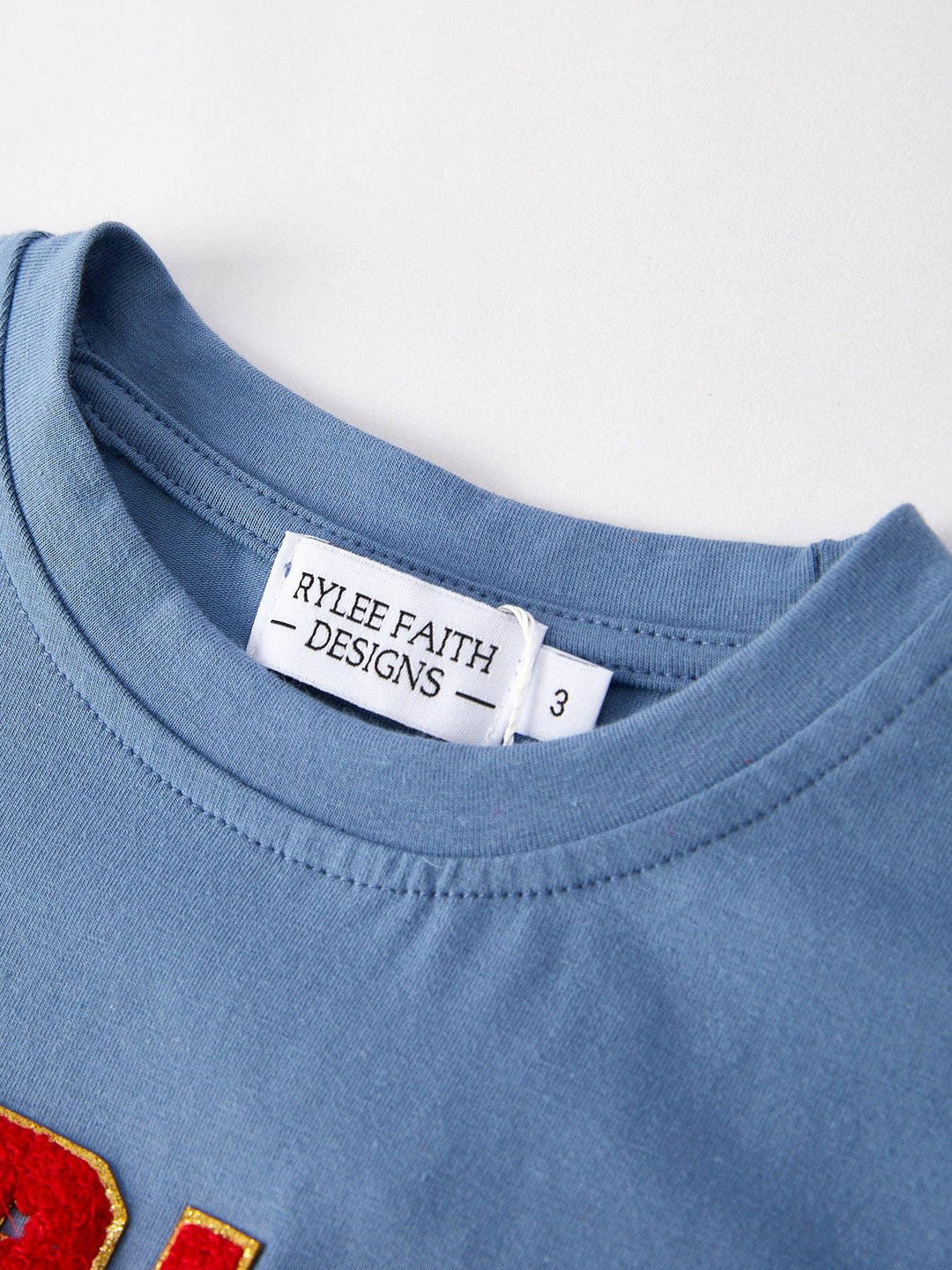 Blue kids tee with Rylee Faith Designs tag and red gold trim, size 3